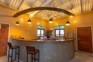 a large kitchen with a bar with two chairs at Legato House in Talpe