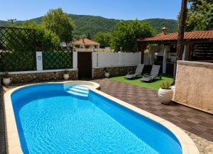 a blue swimming pool in a yard next to a house at ALPE LUXURY ACCOMMODATION Penelope Collection in Olympiada