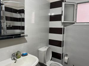 a bathroom with a white toilet and a sink at Sunshine Apartment in Sarandë +12 photos
