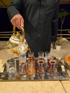 a man is pouring tea into glasses on a tray at Wild Dana Eco Lodge- Hotel-Eco-Camp in Dana +66 photos