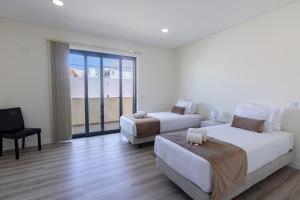 a hotel room with two beds and a balcony at Apartamento Cabine by Algarve Holidays in Quarteira
