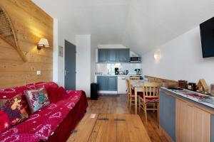 a living room with a red couch and a kitchen at Valmeinier le Miras in Valmeinier