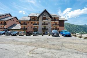a large building with cars parked in a parking lot at Valmeinier le Miras in Valmeinier