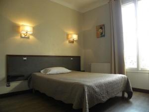 - un lit dans une chambre avec deux lumières sur le mur dans l'établissement Hôtel Le Bellevue - Paris Porte d'Orléans, à Cachan