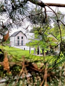 a white house in front of a yard with trees at Chata z Kraja in Józefów