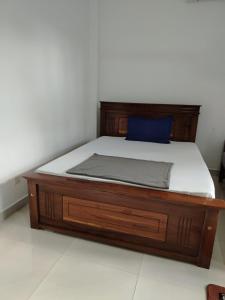 a bed with a wooden frame with a blue pillow on it at Bosadi Guest House Katunayake in Katunayaka