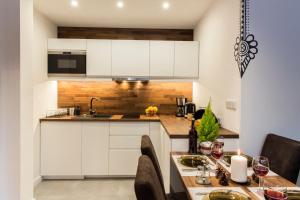 une cuisine avec des placards blancs et une table avec des verres à vin dans l'établissement Apartament Hyrny de Lux, à Zakopane
