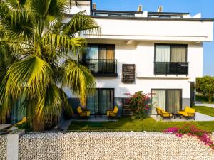 a white building with yellow chairs and a palm tree at Side Mira Palace & Spa in Side