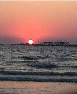 una puesta de sol en la playa con el sol poniéndose en Silver Sands Malpe Beach Villa, en Udupi