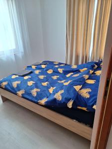 a bed with a blue comforter with gold butterflies on it at Veszei Apartman in Békéscsaba