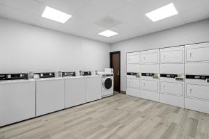 a laundry room with white cabinets and a washer and dryer at HomeTowne Studios by Red Roof Bradenton in Bradenton