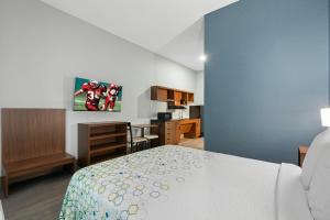 a bedroom with a bed and a room with a desk at HomeTowne Studios by Red Roof Bradenton in Bradenton +27 photos