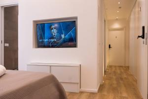 a television hanging on a wall in a bedroom at ABBA ROOMS in Cagliari