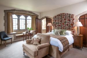 um quarto com uma cama grande e uma cadeira em Amberley Castle- A Relais & Chateaux Hotel em Amberley