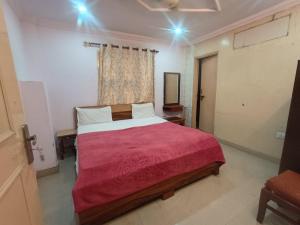 a bedroom with a large bed with a red blanket at Hotel Maa Arya in Lucknow