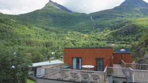 a building with a balcony with mountains in the background at Geirangerbooking in Geiranger