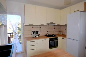 a kitchen with white cabinets and a white refrigerator at Apartments Celebrini in Malinska +18 photos