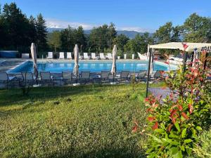 a pool with chairs and umbrellas in a yard at Вила Магнолия in Lakarevo