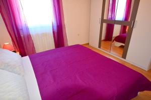 a bedroom with a purple bed and a mirror at Apartments Celebrini in Malinska