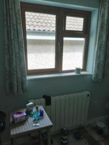 a table in a room with two windows and a radiator at The bungalow in Waterford Manor Station