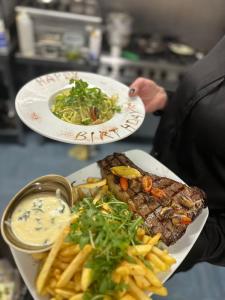 a person holding two plates of food with french fries at Grande Italia Rooms Comfort Italian Hospitality 4 in Ebley +6 photos