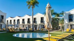 an umbrella and chairs in front of a building at FBC Fortuny Resort - Adults Only in Maspalomas