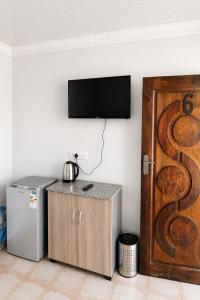 a room with a refrigerator and a television on a wall at Nairobi Guesthouse in Orkney