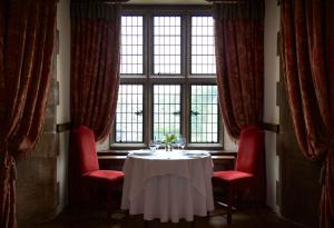 a table in a room with red chairs and a window at Amberley Castle- A Relais & Chateaux Hotel in Amberley