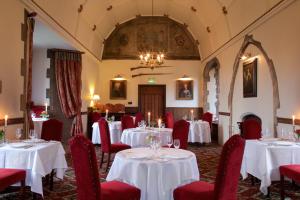 a dining room with white tables and red chairs at Amberley Castle- A Relais & Chateaux Hotel in Amberley