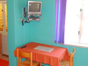 a room with a table and a tv on a blue wall at Apartments Zlatko in Krk
