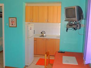 a kitchen with a refrigerator and a tv on the wall at Apartments Zlatko in Krk