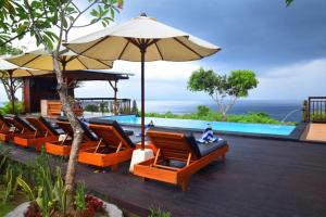 a group of chairs and an umbrella next to a pool at Bataran Garden Cottage in Nusa Penida