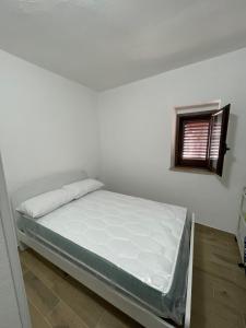 een bed in een witte kamer met een raam bij Dimora AVE in Aieta