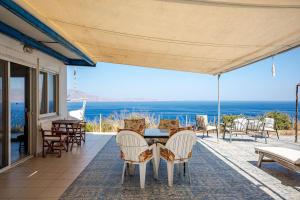 a patio with a table and chairs and the ocean at Michalis Holiday Home in Ravdhoúkha