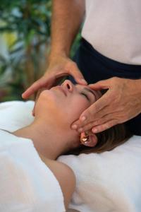 a woman getting her face examined by a massage therapist at FBC Fortuny Resort - Adults Only in Maspalomas