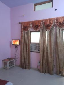a room with a window with curtains and a television at Hare Krishna hotel in Orchha