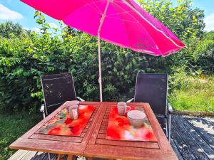 a wooden table with a pink umbrella and chairs at Holiday Home Tiny Haus Heidi by Interhome in Beilngries
