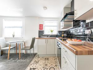 a kitchen with white cabinets and a table with a bowl of fruit at Modern Serviced Apartments in St Helens with Free WiFi Ideal for Leisure or Work Stays by North West Accommodation in Saint Helens