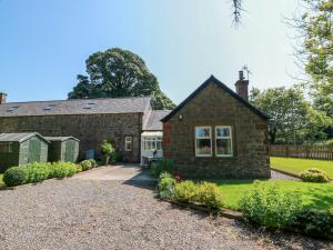 an old brick house with a gravel driveway at Waterside Lodge in Lockerbie
