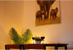 a table with two glasses of wine and a painting on the wall at Lunora Homes in Arusha