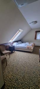 a bedroom with a bed and a chair and a window at Park Hotel in Hévíz
