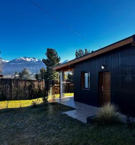 a small black house with mountains in the background at Patagonia in Trevelín