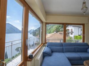 a living room with a blue couch and large windows at Apartment Miralago by Interhome in Oria