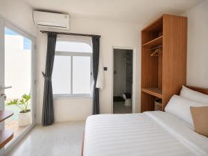 a bedroom with a white bed and a window at Ayodhya Villa Patran in Kejayan