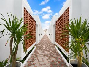 a corridor of white buildings with plants on each side at Ayodhya Villa Patran in Kejayan