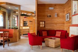 a living room with a red couch and wooden walls at Hotel Funivia in Chiesa in Valmalenco