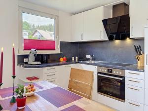 a kitchen with white cabinets and a table and a window at Apartment Blackforest Birdnest by Interhome in Schonach