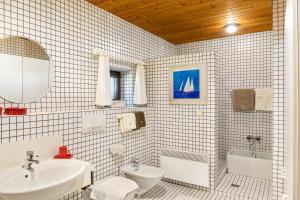 a white tiled bathroom with a sink and a toilet at Villa Mona Lisa in Seefeld in Tirol +28 photos