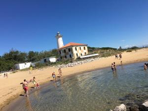 un groupe de personnes sur une plage avec un phare dans l'établissement Villaggio Dei Gelsomini, à Bibione