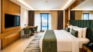 a hotel room with a large bed and a flat screen tv at The Crown Puducherry in Pondicherry